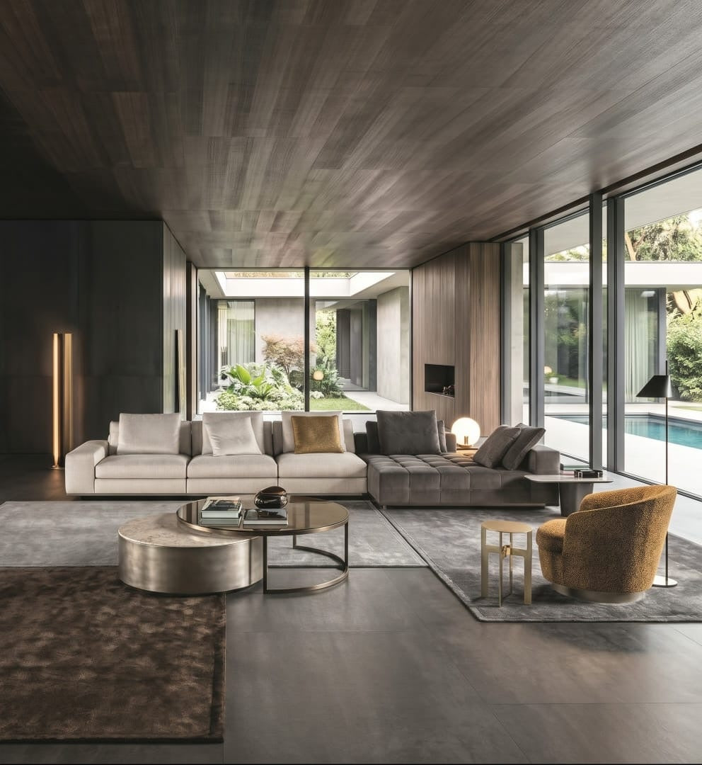 Open-plan lounge with ivory and grey modular sofa, bouclé armchair and glass walls to the garden